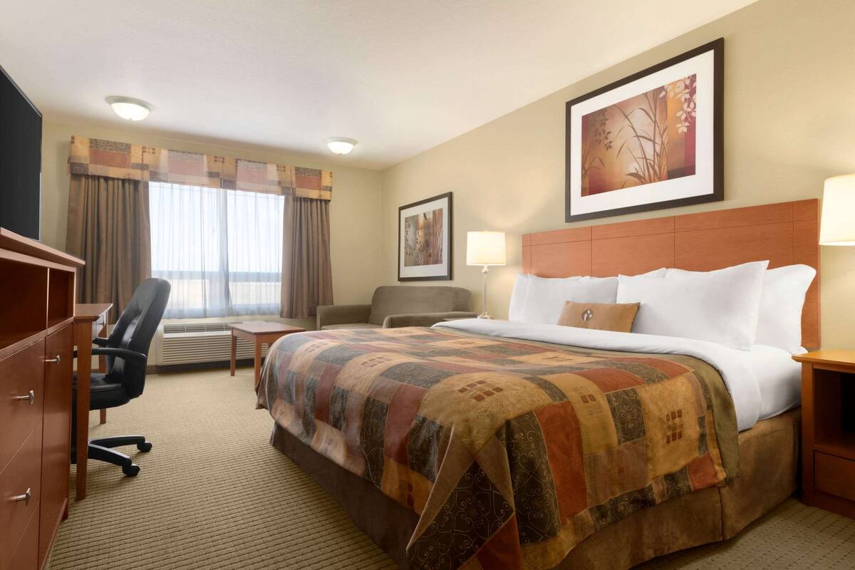 Una habitación de hotel con una cama grande, un escritorio, una silla y un armario.