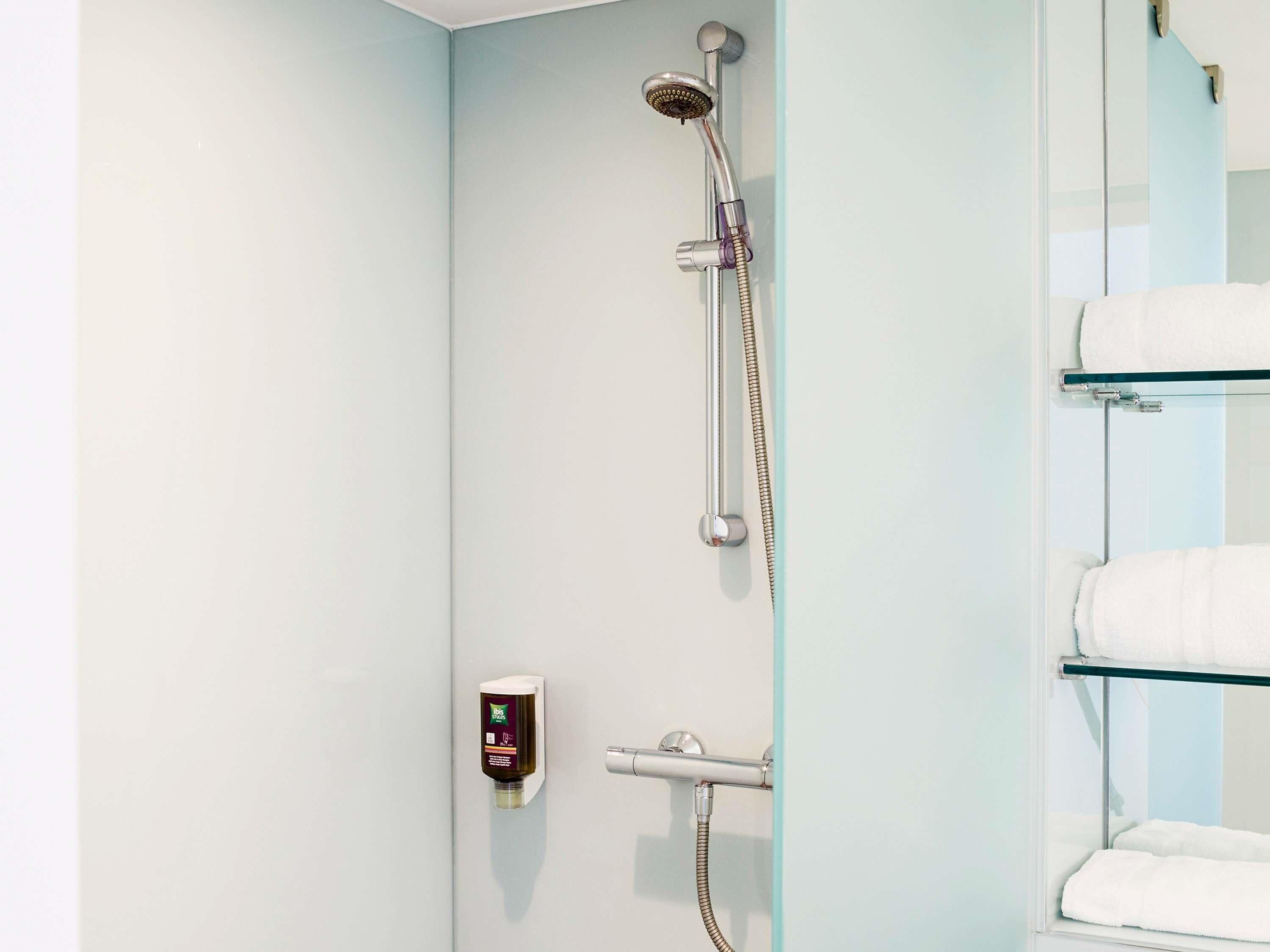 A shower with a handheld showerhead, a handheld shower attachment, and a wall-mounted control panel.