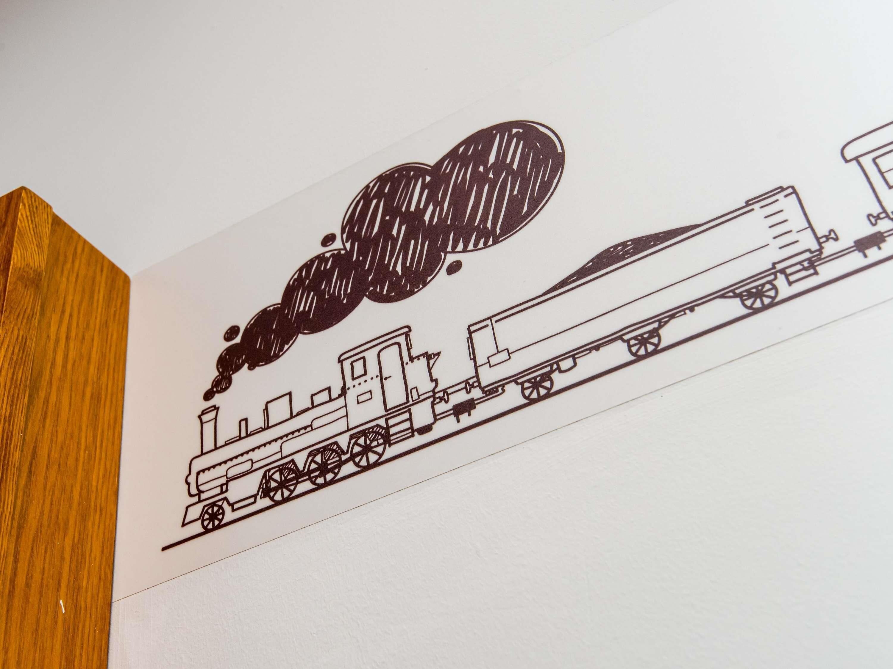 Dibujo en blanco y negro de un tren sobre una pared blanca.
