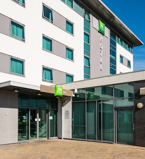 A modern hotel with a flat facade, large windows, and a green sign indicating it is part of the ibis Styles hotel chain.