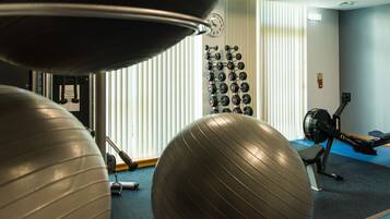 A gym with exercise balls, dumbbells, and a rowing machine.