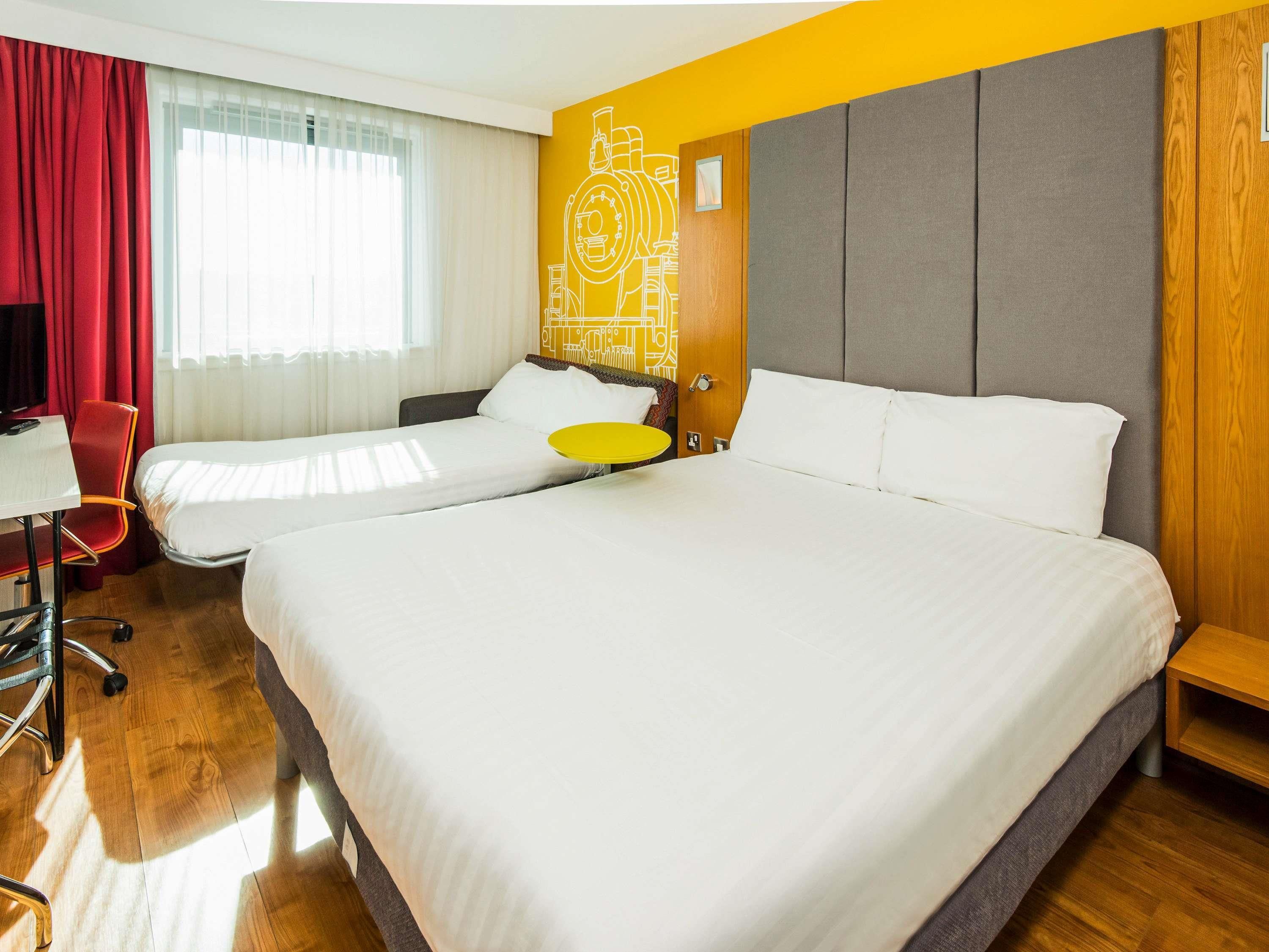 Habitación de hotel con dos camas, un escritorio y una silla.
