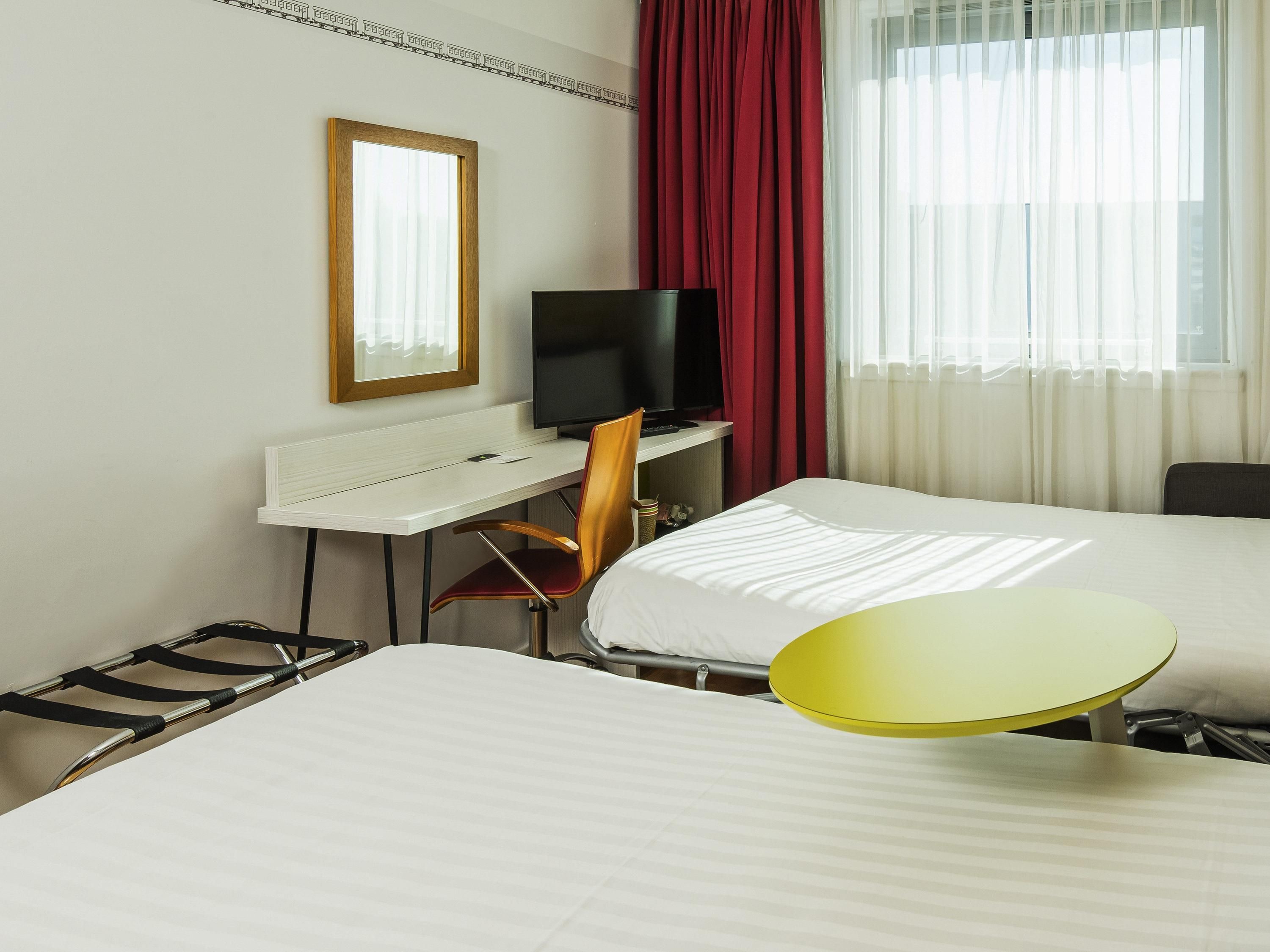 A hotel room with a bed, a desk with a computer, a television, and a chair.