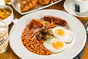 A plate of breakfast food including beans, eggs, and sausages.