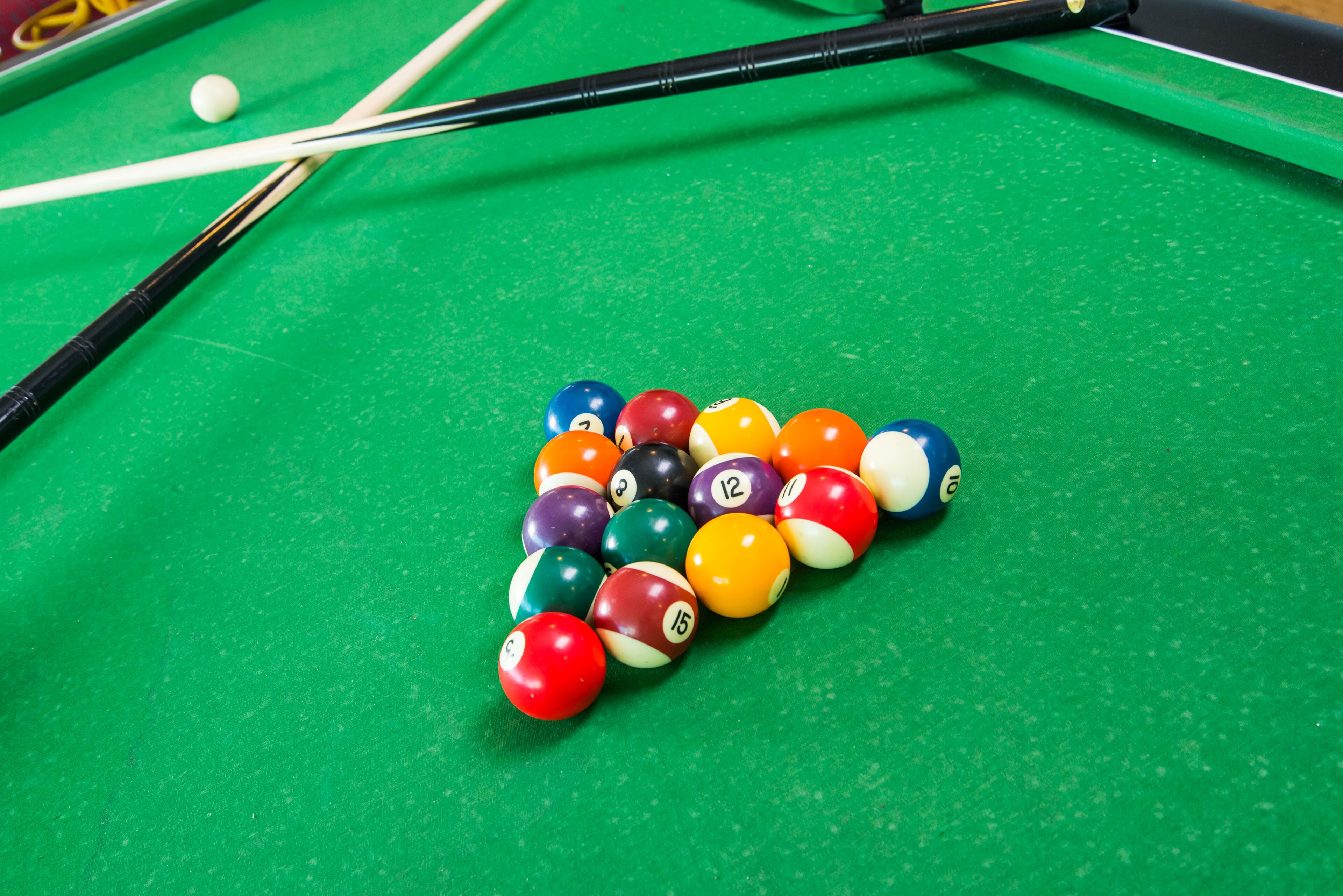A pool table with a set of billiard balls arranged in a triangle formation.