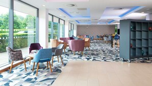 A modern hotel lobby with large windows, a patterned floor, and a variety of seating options. - ibis Styles Crewe (Crewe)