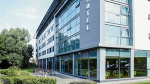 A modern hotel with a glass facade, outdoor seating area, and a sign indicating 'ibis Styles'. - ibis Styles Crewe (Crewe)