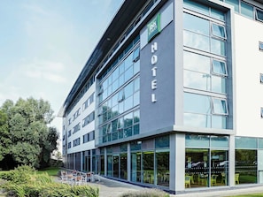 A modern hotel with a glass facade, outdoor seating area, and a sign indicating 'ibis Styles'. - ibis Styles Crewe (Crewe)