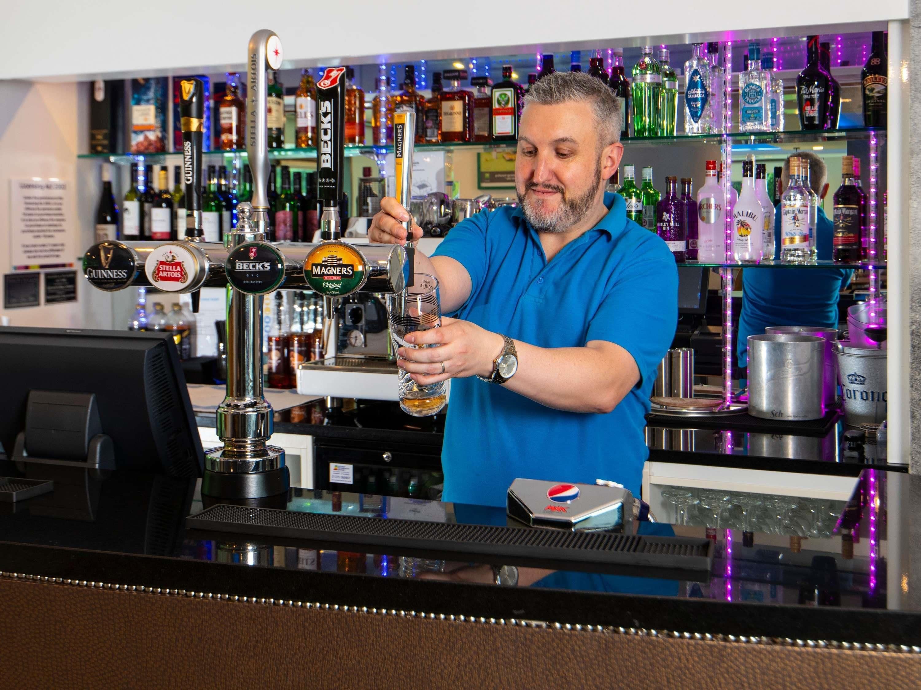 Um bartender servindo uma bebida de uma torneira com a inscrição 'BECKS' em um copo.