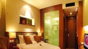 Ein Hotelzimmer mit Bett, Nachttischlampen, einem Spiegel und einem Fernseher.
