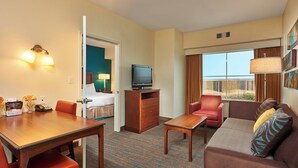 A hotel room with a dining table, a sofa, a television, and a window with curtains. - Residence Inn by Marriott Midland (Midland)