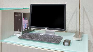 A computer desk with a monitor, keyboard, mouse, and a printer.