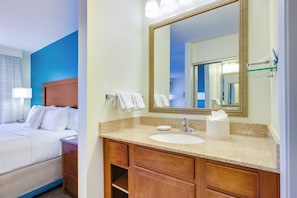 A hotel room with a bed, a bathroom with a sink, mirror, and toiletries. - Residence Inn by Marriott Midland (Midland)