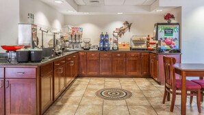 Una cocina moderna con armarios de madera, una estación de café y un comedor con mesa y sillas.