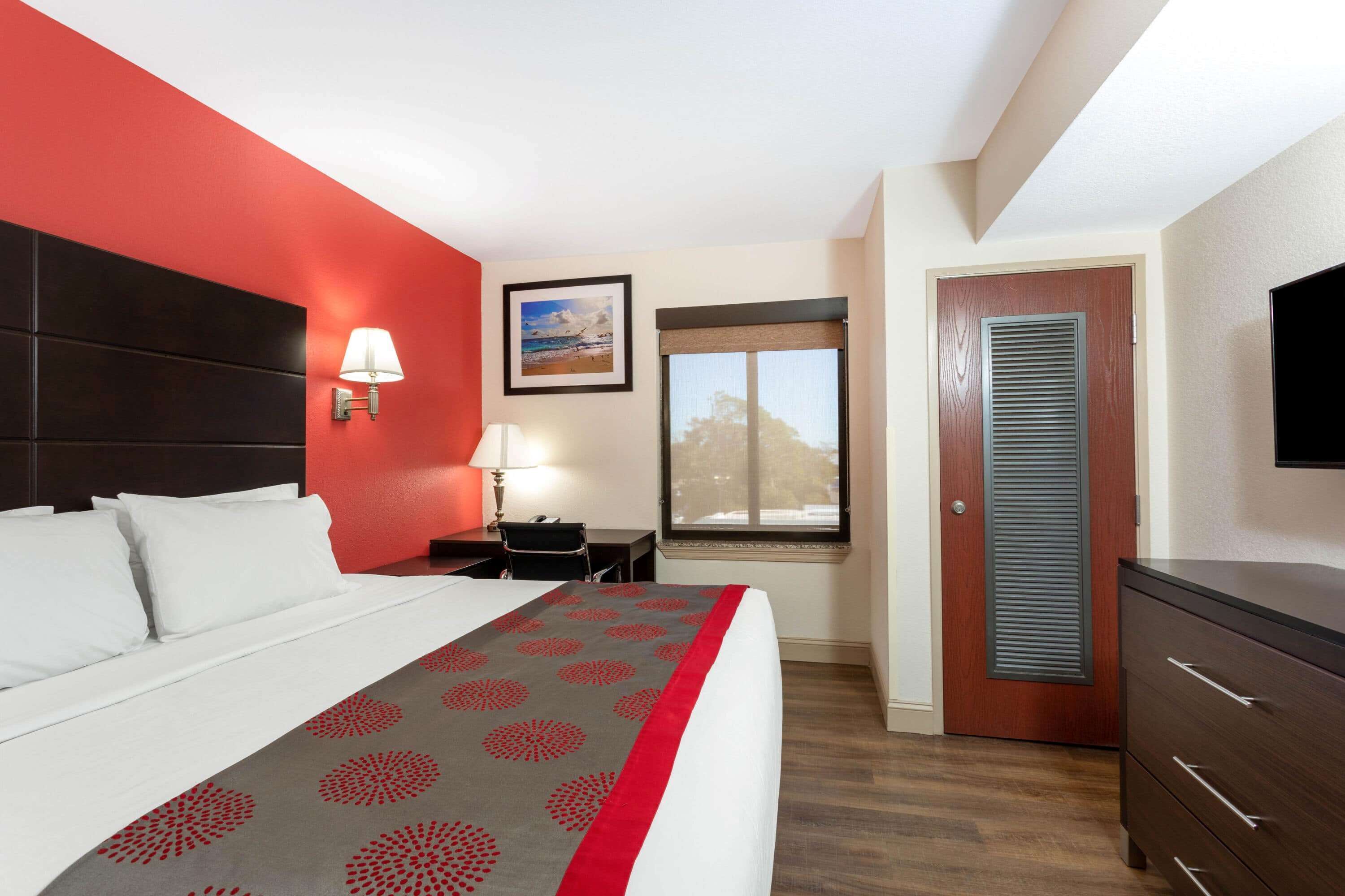 Una camera d'albergo con un letto, una scrivania, una sedia, una finestra e una televisione.