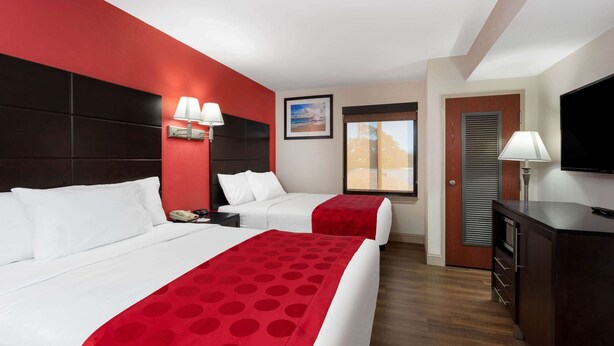 Habitación de hotel con dos camas, televisión, escritorio y ventana con vistas.