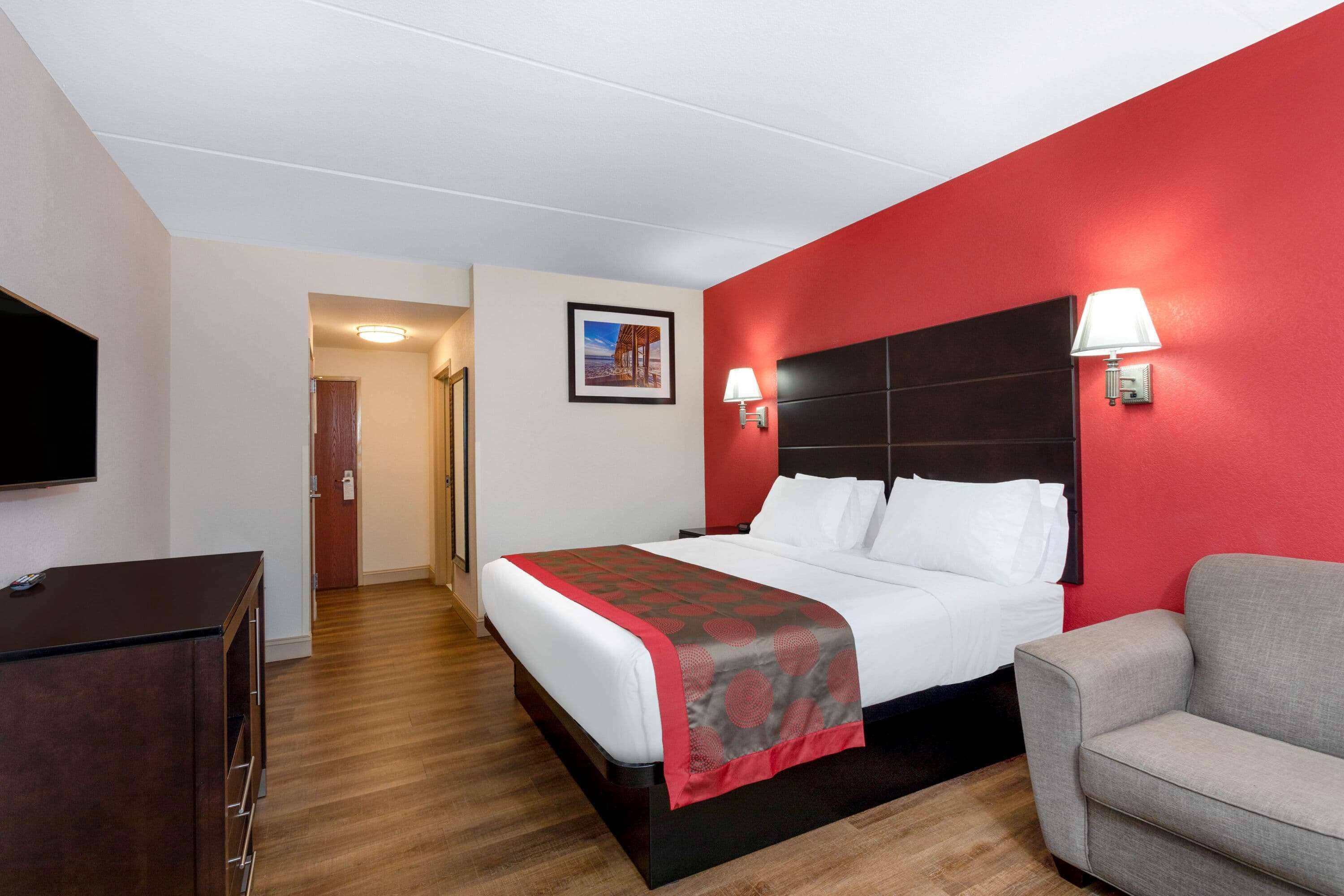 Hotellihuone, jossa on sänky, televisio, työpöytä ja tuoli.