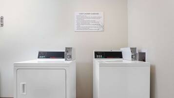A laundry area with two front-loading washing machines and a guest laundry guidelines sign on the wall.
