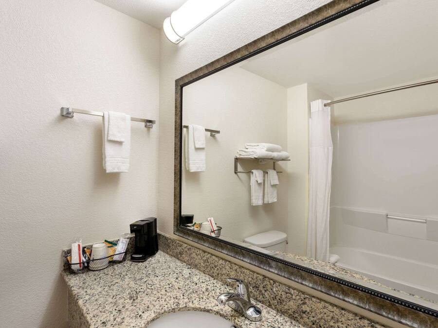 A bathroom with a sink, mirror, and shower.
