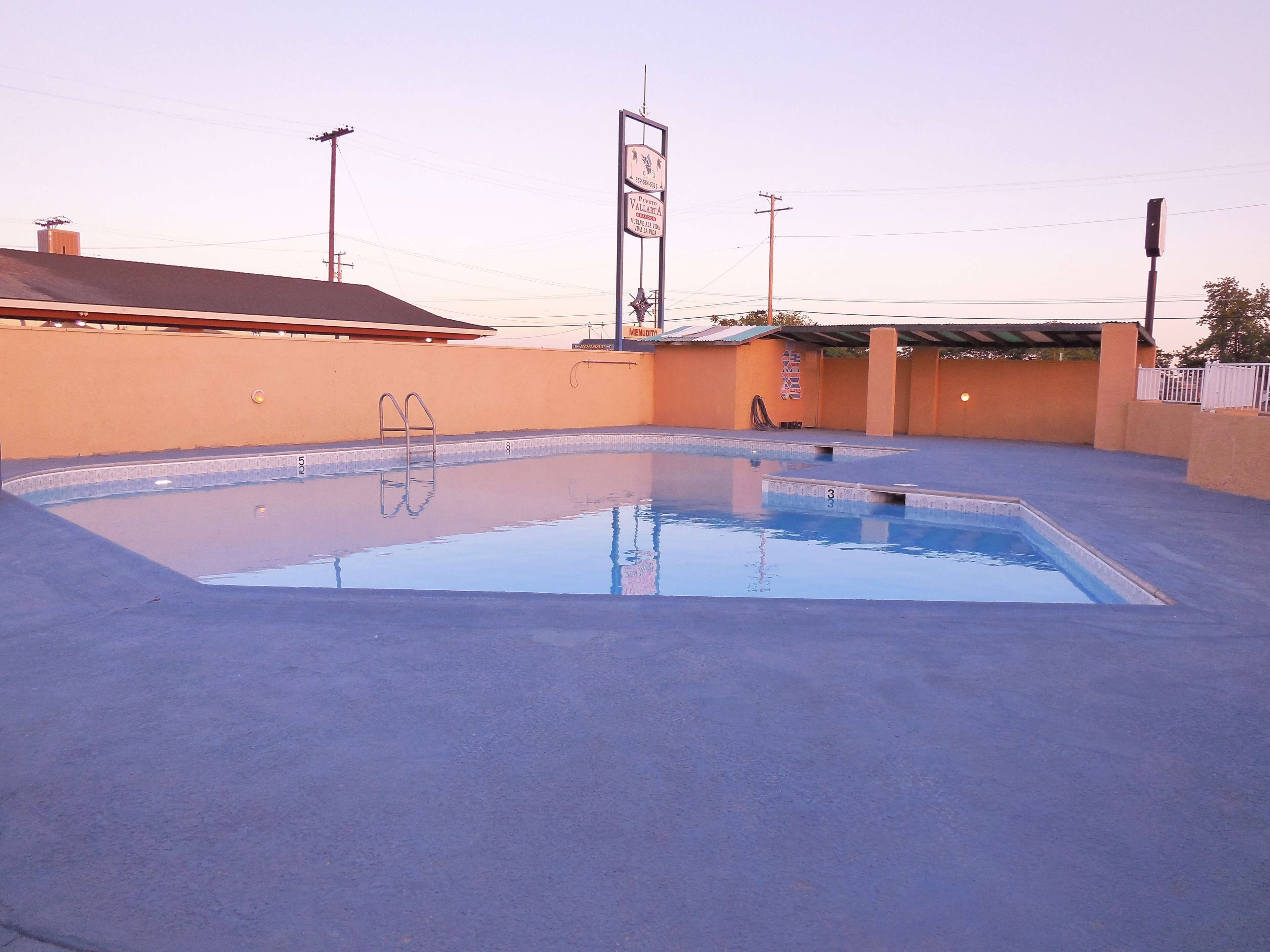 Une piscine extérieure avec un escalier en métal et un panneau d’affichage en arrière-plan.