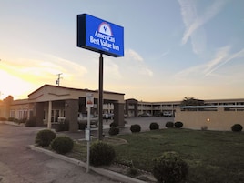 Un hotel Americana Best Value Inn con un cartel, una zona de estacionamiento y un edificio de varios pisos.