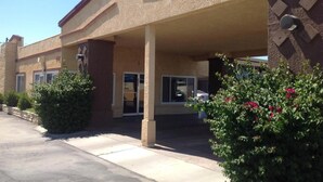 A building with a covered entrance, large windows, and a parking lot. - Americas Best Value Inn Hanford (Hanford)