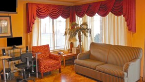 A living room with a sofa, armchair, and a desk with a computer. - Americas Best Value Inn Hanford (Hanford)