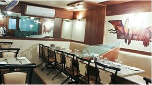 Un restaurante con una barra larga, varias mesas y sillas.