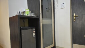 Una pequeña kitchenette con un refrigerador, un microondas y una cafetera sobre una encimera de madera.
