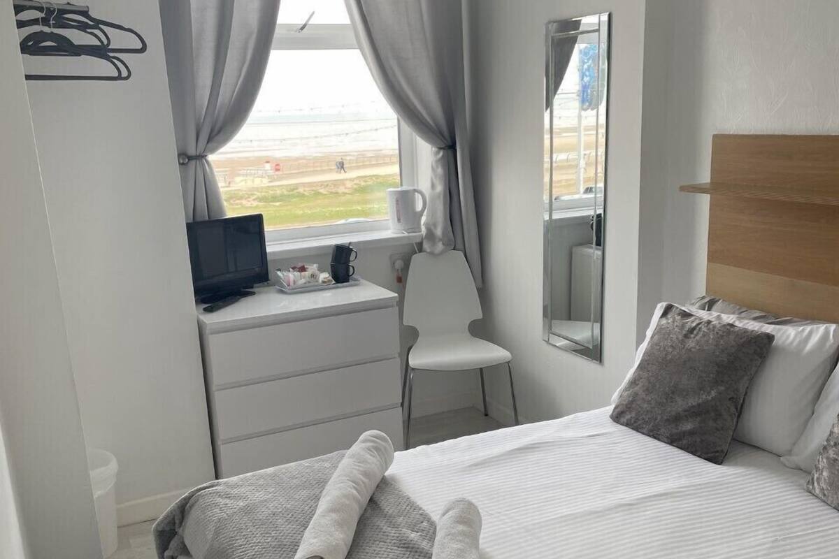 A neatly arranged bedroom with a bed, a desk, and a chair.
