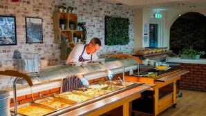 A buffet setup with multiple serving stations, a brick wall, and a green wall with plants. - The Craig-Y-Don Hotel (Blackpool)