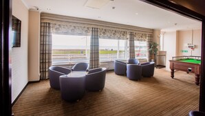 A room with a pool table, comfortable seating, large windows with curtains, and a view of the beach. - The Craig-Y-Don Hotel (Blackpool)