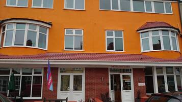 A two-story building with a bright orange facade, multiple windows, and a red-tiled roof.