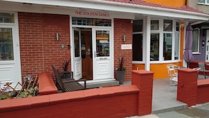 A brick building with a red and white facade, labeled "The Golden Sands Guest House." - The Golden Sands (Blackpool)
