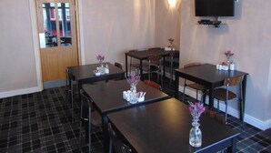 A dining area with a chandelier, a flat-screen TV mounted on the wall, and a plaid-patterned floor. - The Golden Sands (Blackpool)