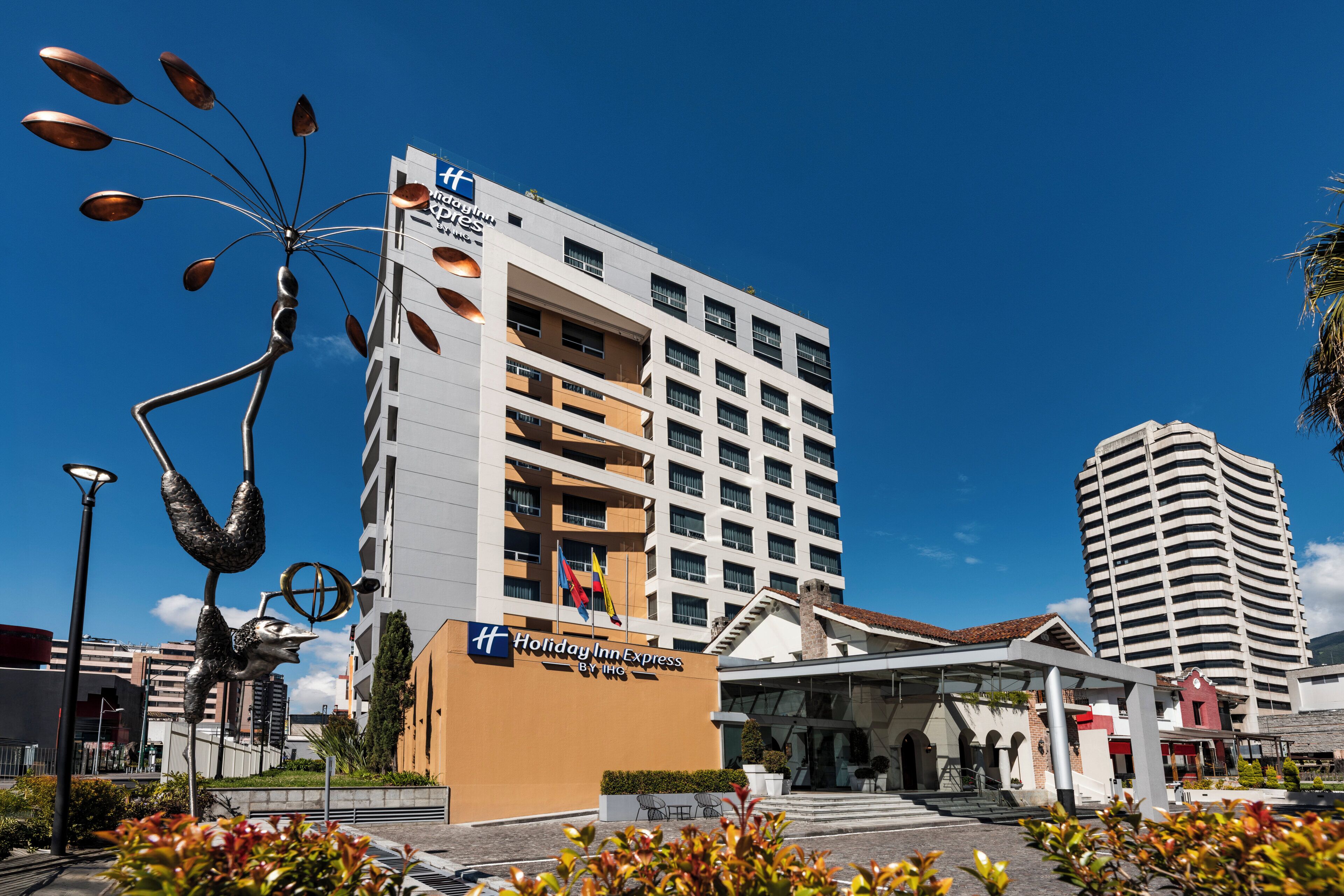 Edifici d'Holiday Inn Express amb un disseny modern, diversos pisos i un cel blau clar.