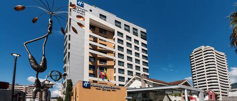A Holiday Inn Express building with a modern design, multiple floors, and a clear sky.