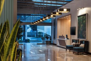 Un vestíbulo moderno con mostrador de recepción, zona de estar y un ventanal que ofrece vistas al exterior.