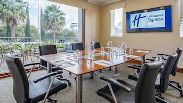A conference room with a large table, chairs, and a Holiday Inn Express sign on the wall.