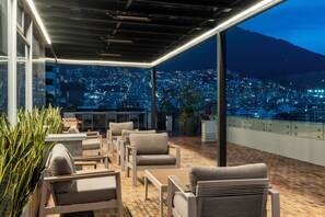 An outdoor seating area with chairs and tables, overlooking a cityscape at night. - Holiday Inn Express Quito by IHG (Quito)