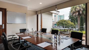 A conference room with a long table, chairs, water bottles, and a whiteboard.