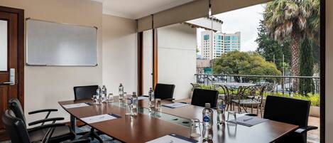 A conference room with a long table, chairs, water bottles, and a whiteboard.
