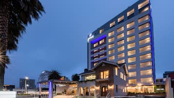 Un hotel a più piani dal design moderno, con un ingresso evidente caratterizzato da gradini e un'area coperta.