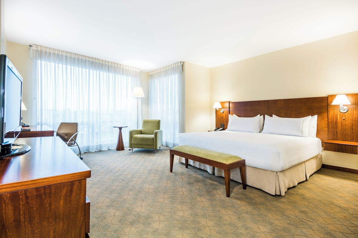 Una habitació d'hotel amb un llit gran, una taula de treball, una cadira i una televisió.