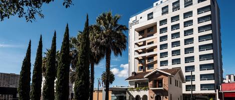 A multi-story hotel with a modern design, featuring a prominent entrance with steps and a covered area.