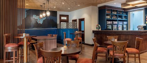 Un ristorante con tavoli e sedie in legno, un'area bar con scaffali pieni di bottiglie e un soffitto decorativo.