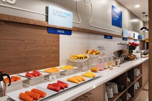 A buffet with labeled sections for fruit and cereal, and a sign indicating a breakfast start. - Holiday Inn Express Quito by IHG (Quito)