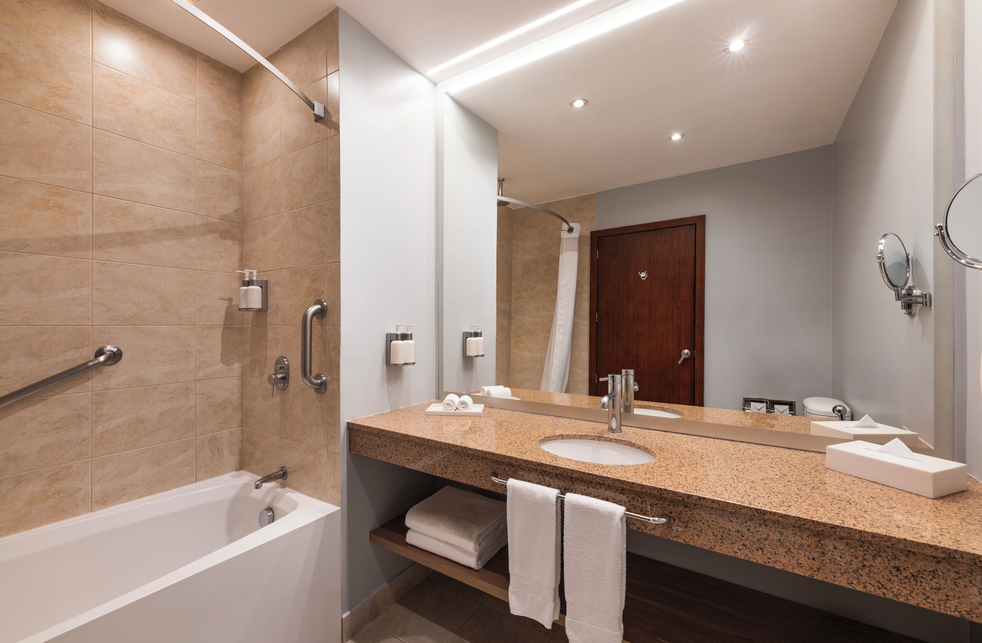 Un baño moderno con bañera, un lavamanos con un espejo grande y zona de ducha.