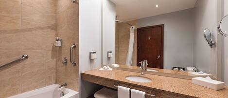 Un baño moderno con bañera, un lavamanos con un espejo grande y zona de ducha.
