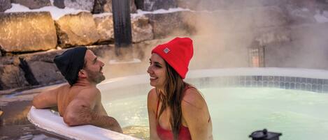 A hot tub area with a stone wall and a wooden deck.